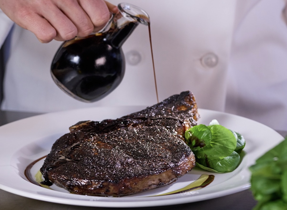 Bife de ancho suculento e grelhado sobre tábua de madeira, acompanhado de alecrim e sal grosso em fundo rústico