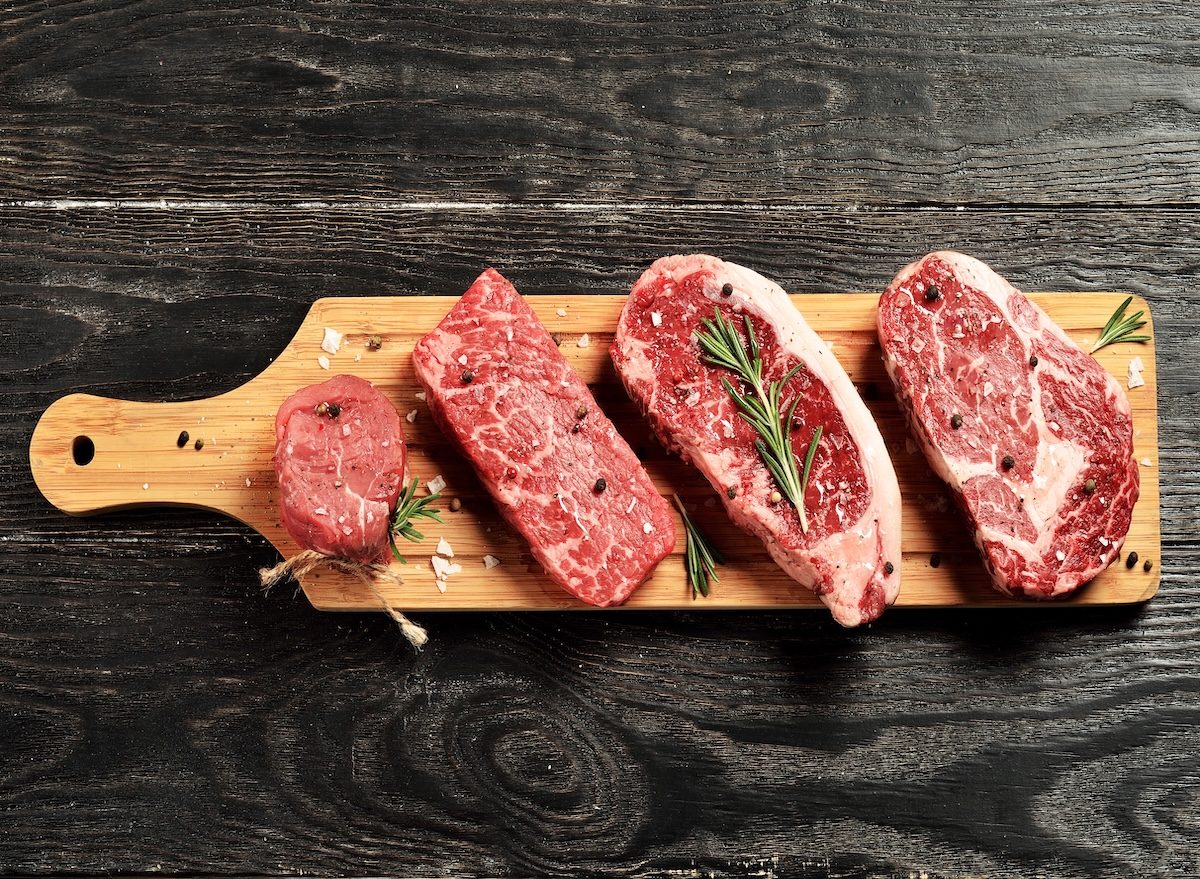 Tábua de madeira com onglet, bavette, flat iron, denver steak e bochechas de boi expostos ao lado de faca