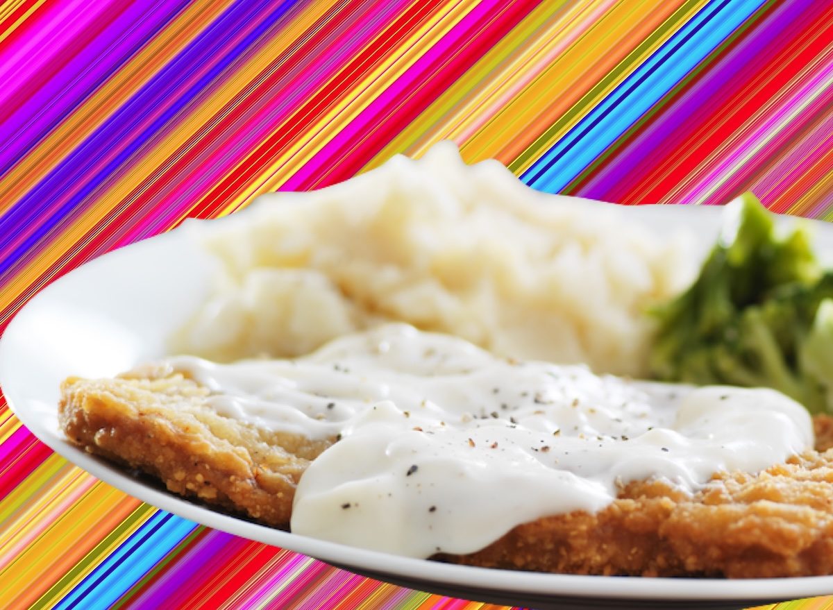 Bife empanado dourado ao lado de folhas verdes, batata doce assada e garrafa de água mineral