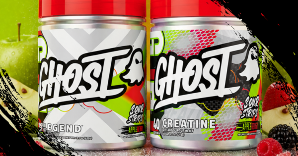 Pote da Ghost Creatine Appleberry ao lado de um copo com shake, maçãs vermelhas e halteres sobre um tapete de treino