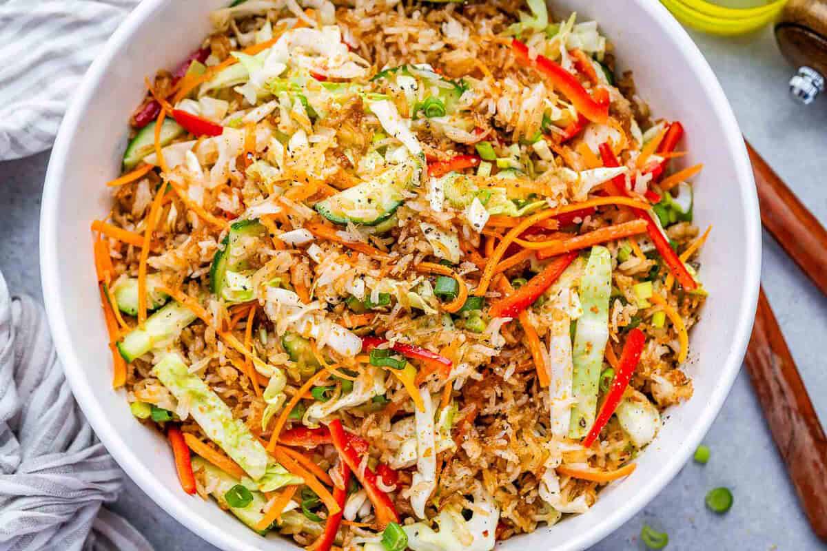 Arroz crocante ao lado de legumes frescos e um molho de gergelim