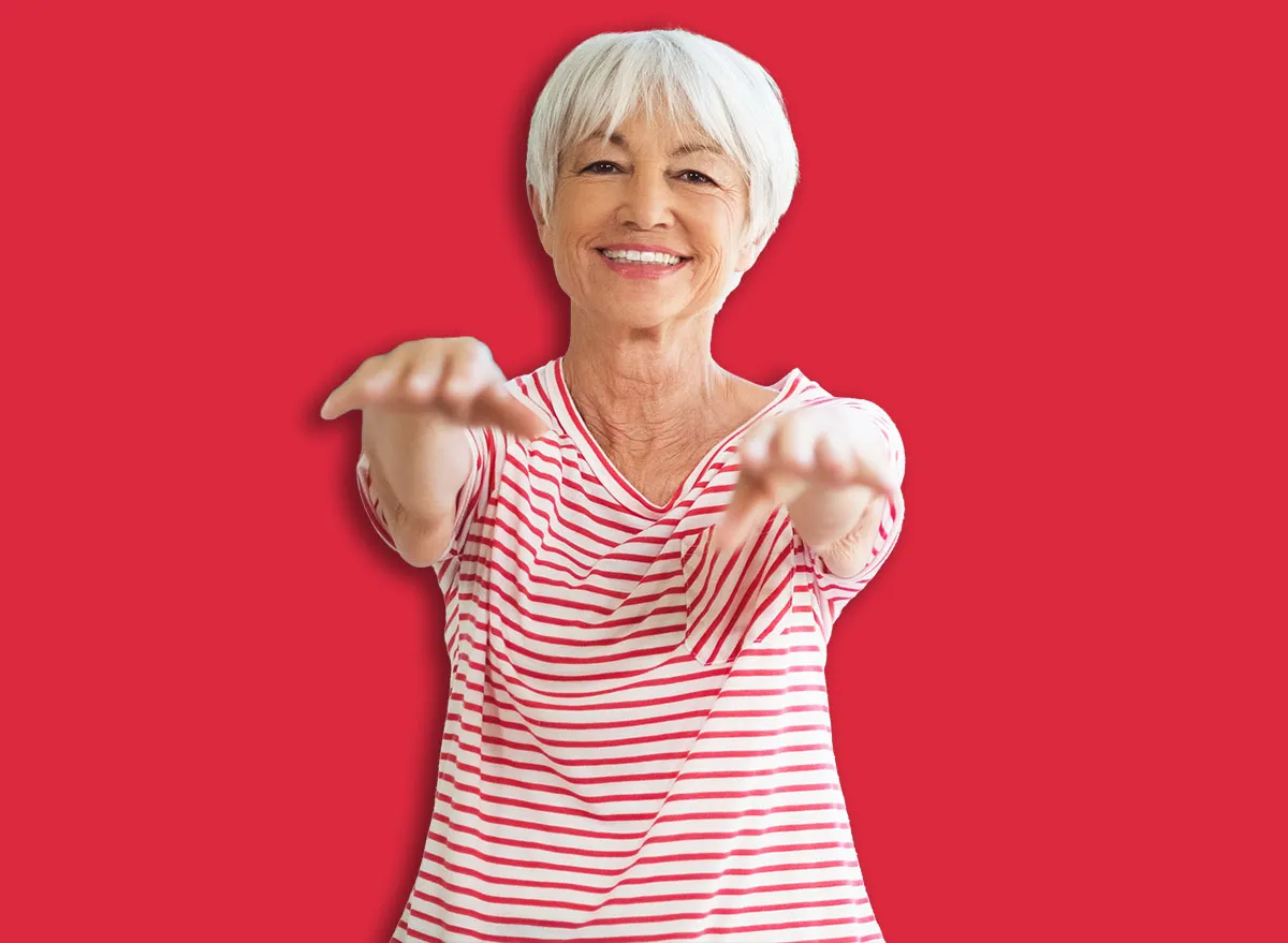 Uma pessoa de meia-idade em pé sobre uma cama elástica, equilibrando-se com um copo de água na mão