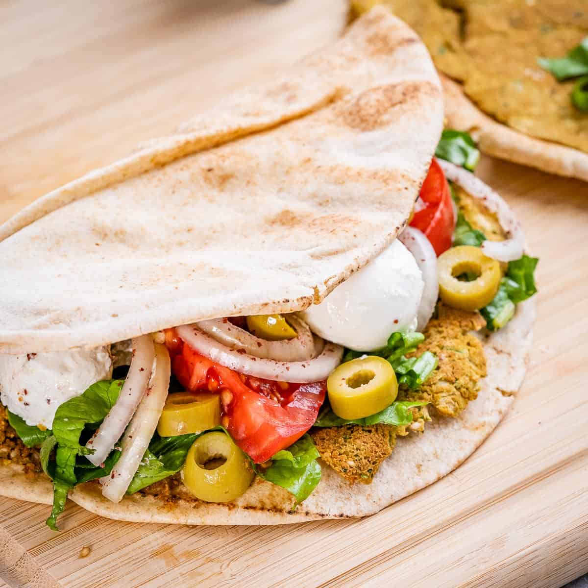 Pita crocante recheada com falafel, labneh e cebola sumac