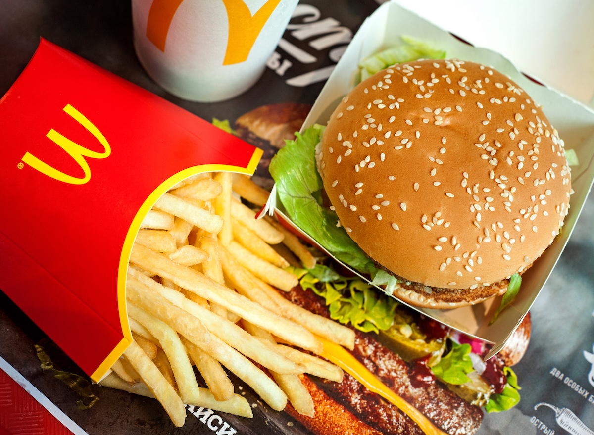 Hambúrguer suculento sobre uma mesa rústica, cercado por batatas fritas douradas e uma embalagem clássica de papel