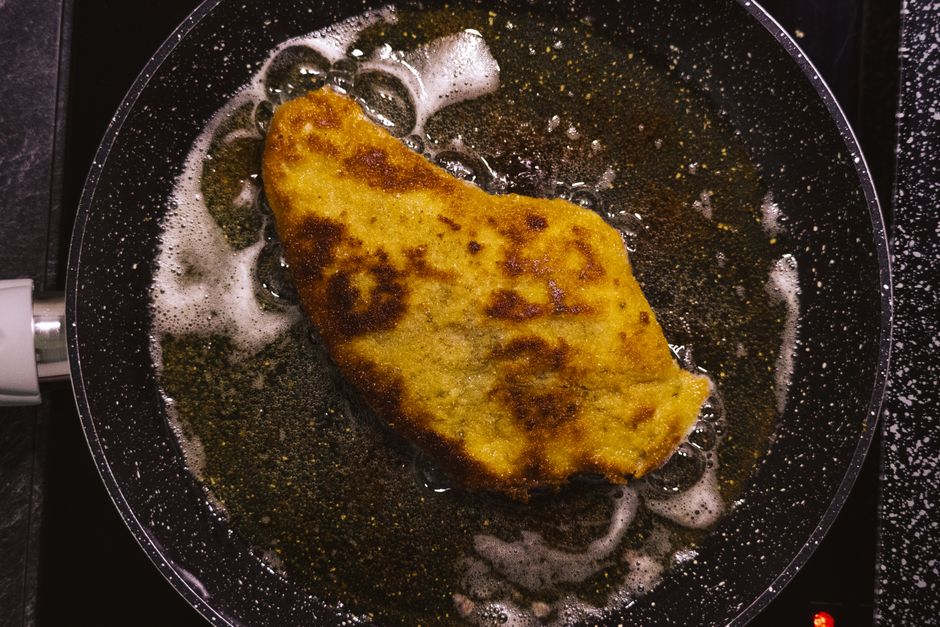Um filé de peixe empanado crocante, com pedaços de peixe cobertos por uma camada de empanadura e óleo quente