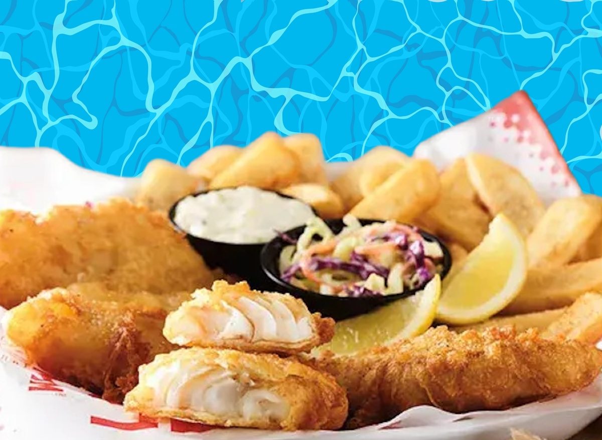 Peixe empanado dourado ao lado de batatas crocantes, com limão e molho tártaro sobre uma tábua de madeira