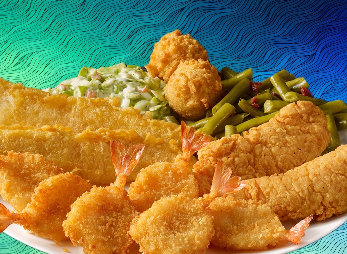 Um peixe frito crocante em cima de uma cama de batata-doce frita e legumes grelhados