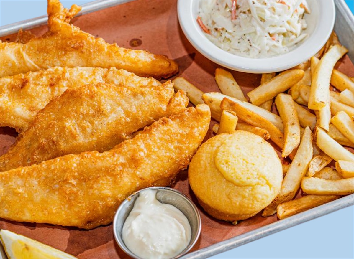 Um prato de peixe frito com legumes e uma porção de arroz ao lado