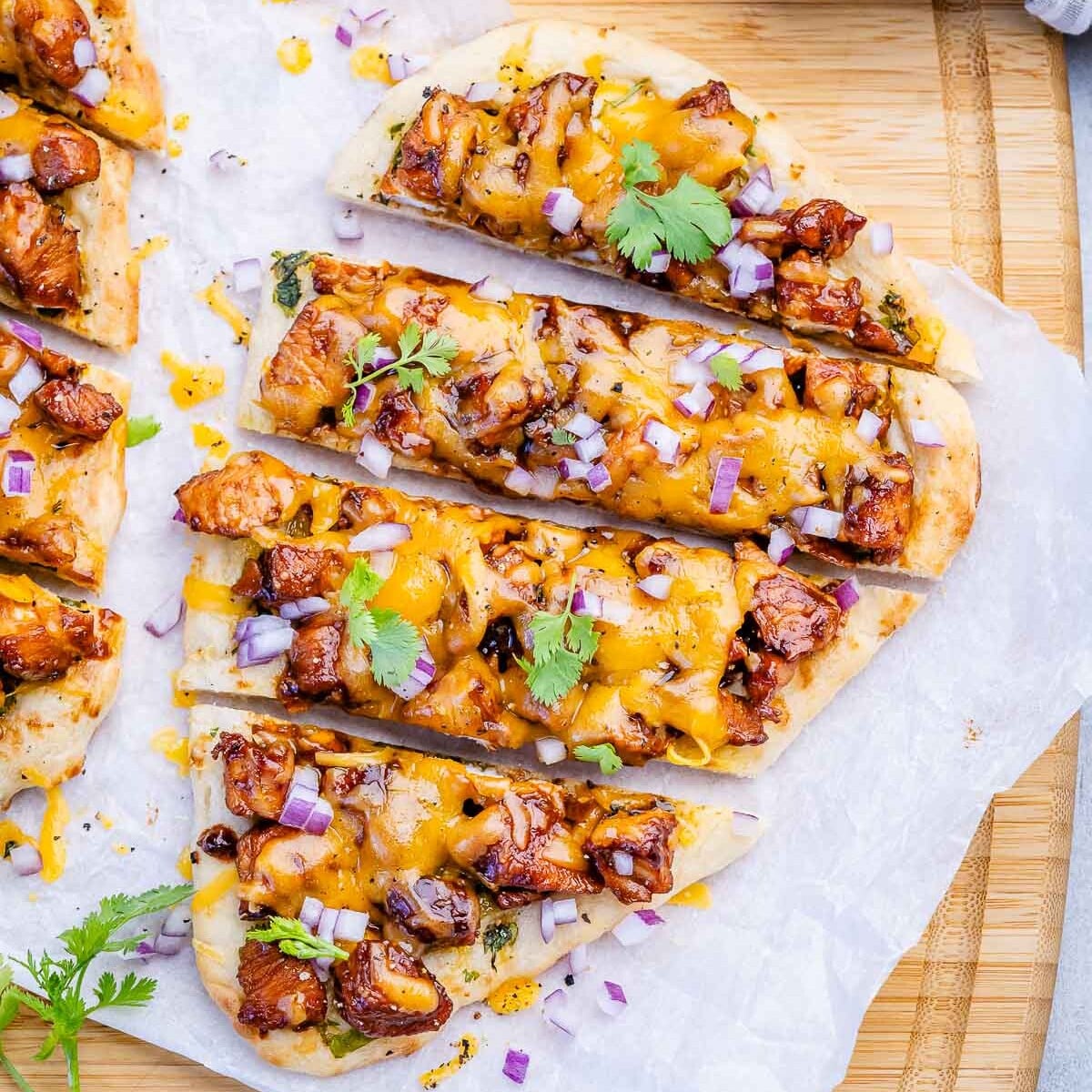 Um prato de flatbread de frango BBQ com frango dourado, molho grosso e fatias de queijo derretido