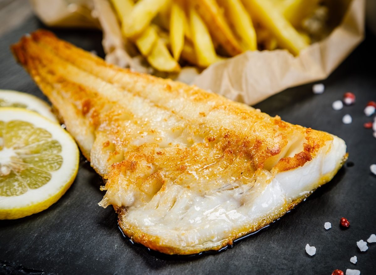 Um peixe flounder fresco, com sua carne branca e textura macia, é exibido em uma prateleira de supermercado