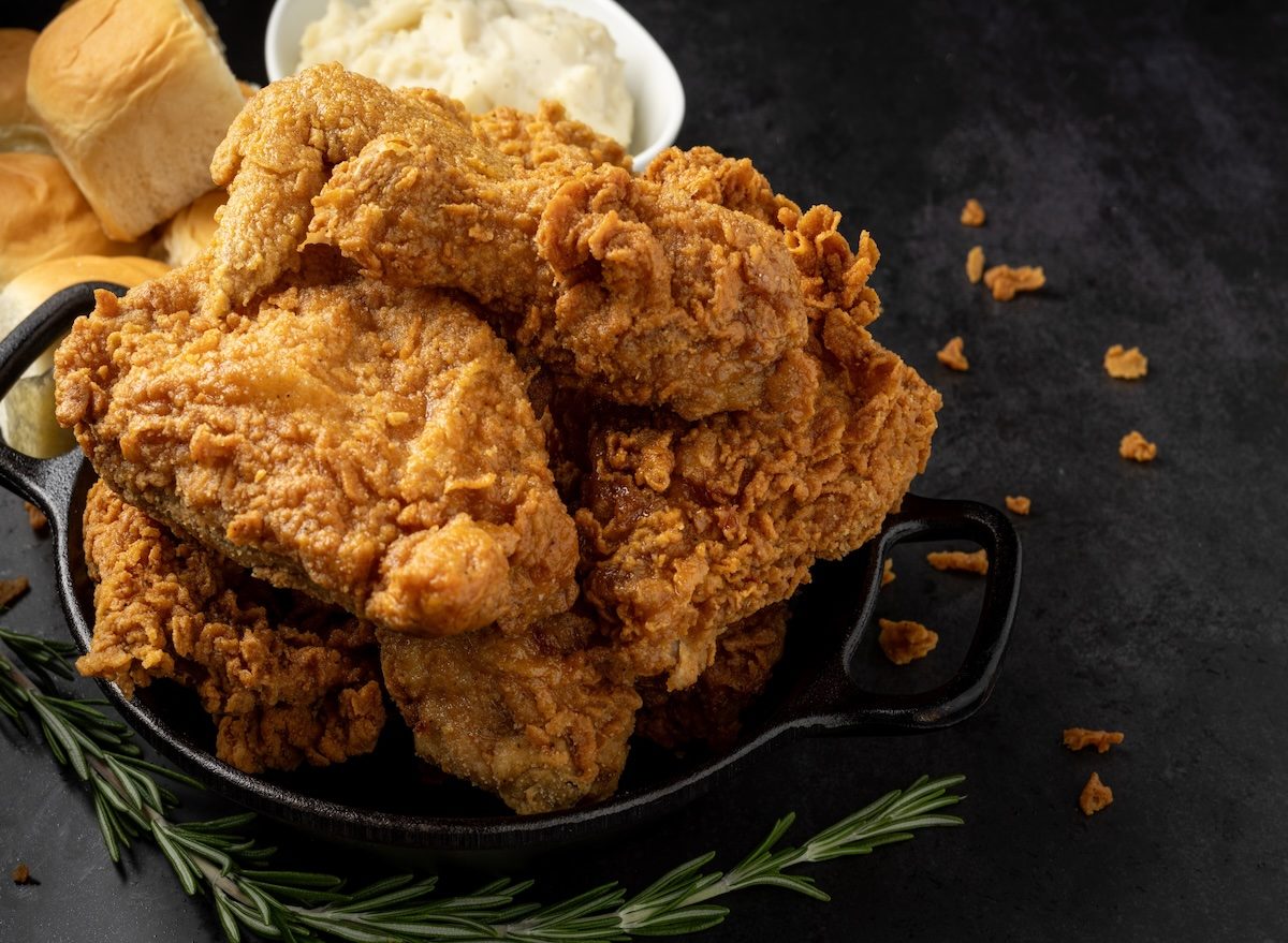 Frango à milanesa dourado ao lado de purê de batata cremoso em prato branco sobre tábua de madeira