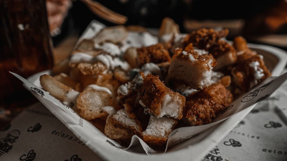 Um frango frito saudável, com textura crocante e cor dourada, é servido com folhas de alface fresca e legumes crus ao lado