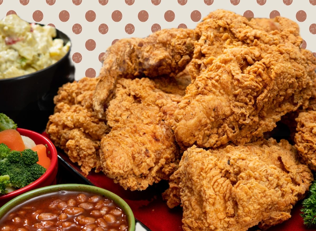Um frango frito crocante com pele dourada e carne macia, acompanhado de legumes frescos e folhas verdejantes