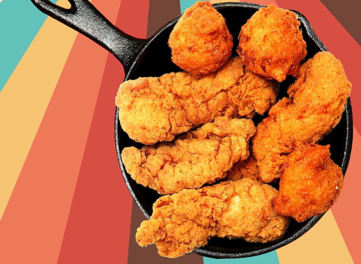 Frango frito dourado ao lado de hush puppies crocantes, com limão e molho picante sobre uma tábua rústica