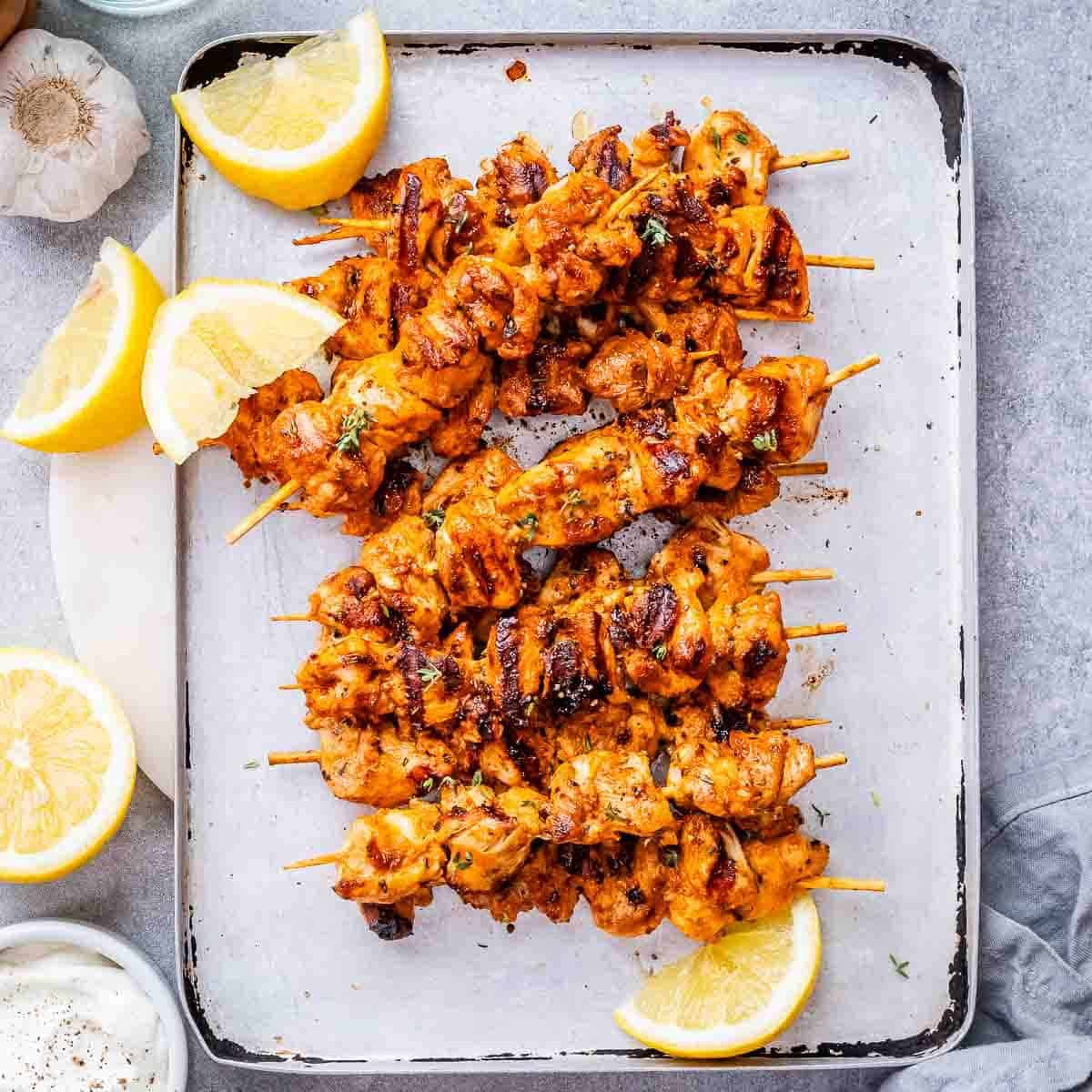 Peitos de frango suculentos em uma tigela com iogurte, ervas frescas e temperos sobre uma bancada de cozinha rústica