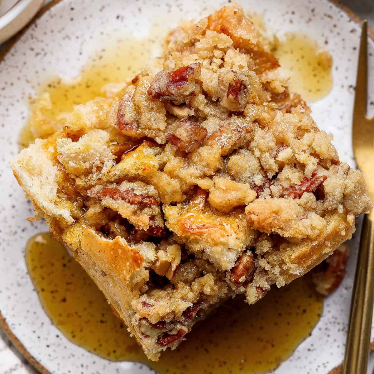 Casserole de rabanada dourada em refratário, decorada com frutas vermelhas frescas e um fio de mel sobre a mesa