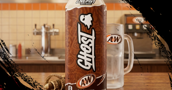 Pessoa sorrindo enquanto segura uma lata de Ghost Energy A&W Root Beer em um ambiente de academia de ginástica