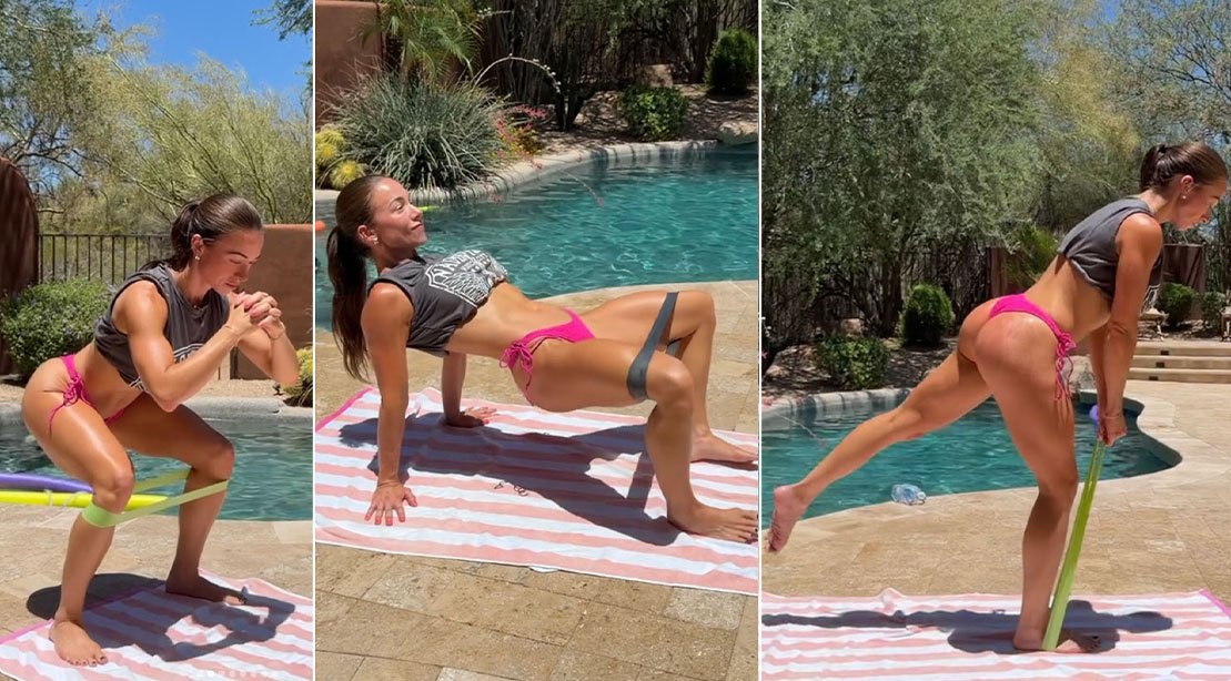 Uma pessoa faz exercícios de glúteos com uma faixa elástica em um ambiente de treino com equipamentos de ginástica