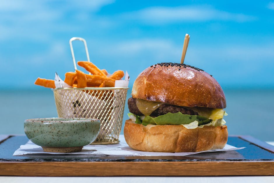 Hambúrguer suculento de Wagyu com marmoreio visível em uma tábua de madeira, acompanhado de vegetais frescos