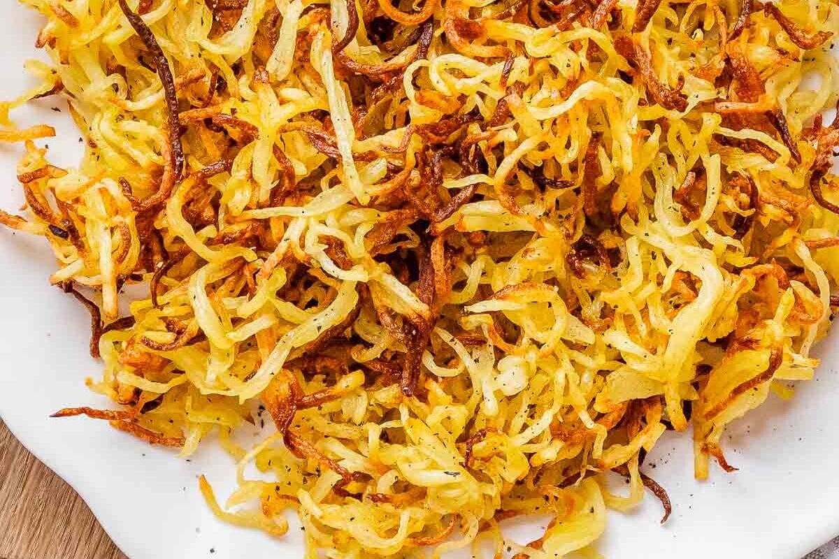 Tiras de batata crocantes em camada única na air fryer, com spray de óleo e ar quente circulando ao redor