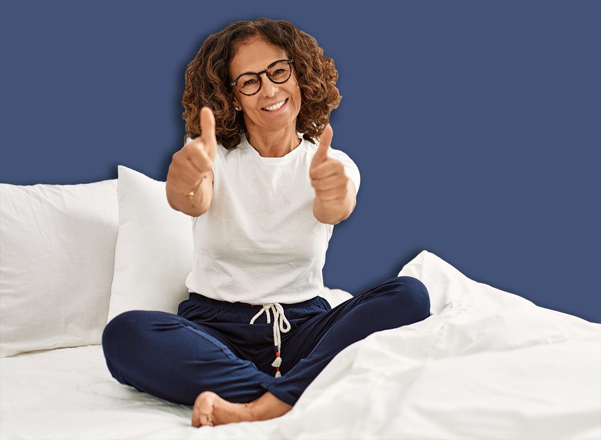 Uma mulher acordada na cama, fazendo alongamentos leves com as pernas e quadris