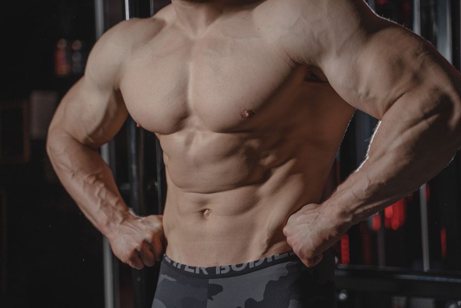 Atletas levantam halteres de 100 kg enquanto seguram barras de whey, com músculos visivelmente definidos e simétricos
