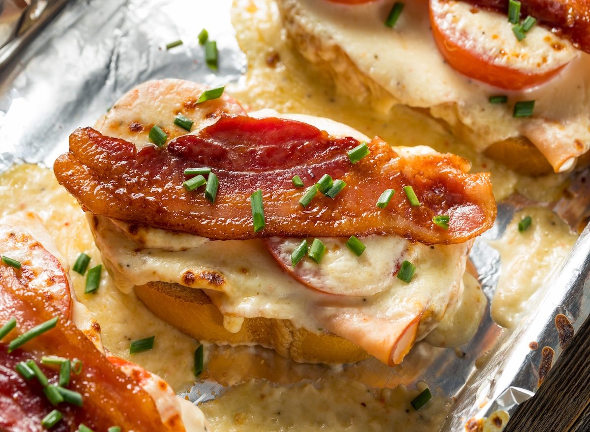 Um sanduíche de peru assado, bacon e molho cremoso, com fatias de pão tostado e vegetais frescos