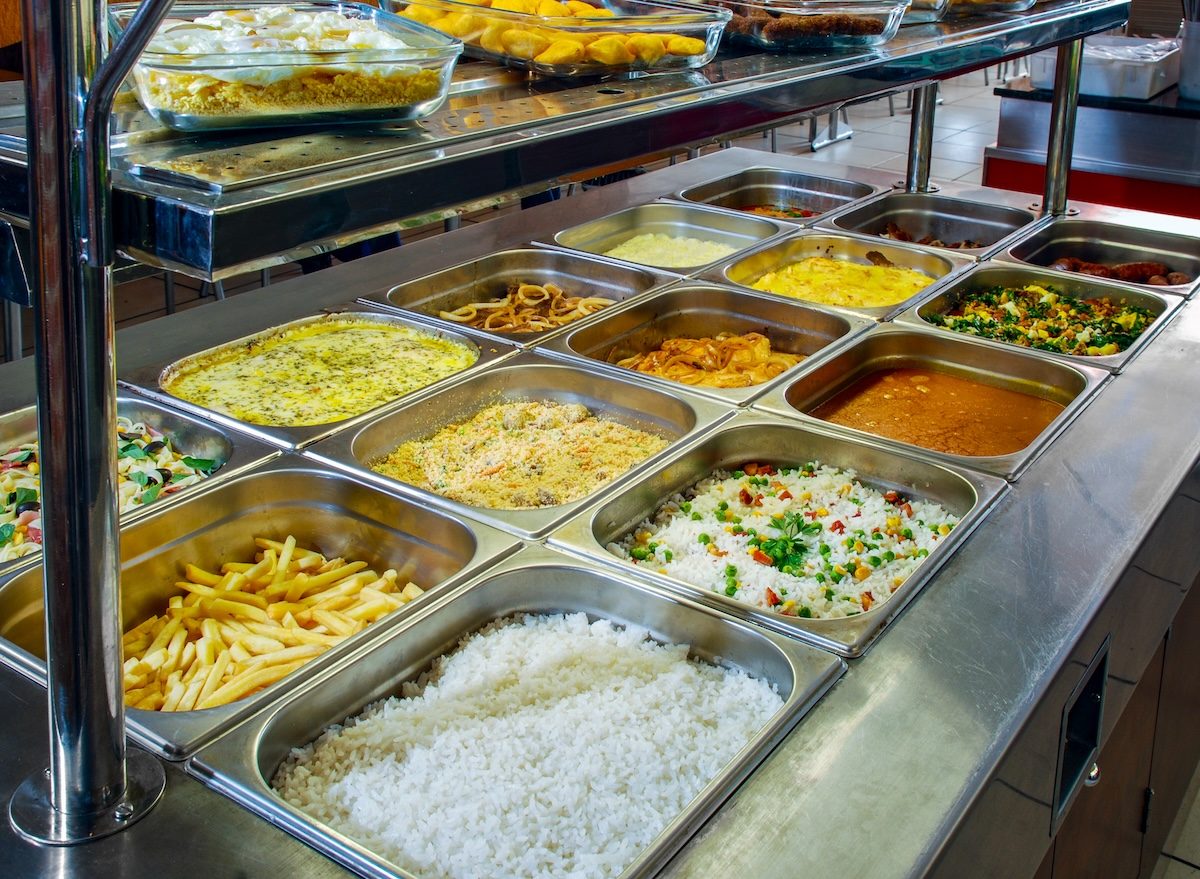 Pratos quentes e frescos, como saladas de frango e vegetais, e pratos de arroz e legumes, são servidos em mesas de buffet