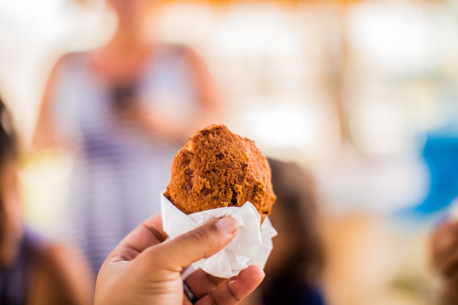 Um prato de hush puppies fritos, com vários bolinhos crocantes e um pincel de óleo dourado no fundo