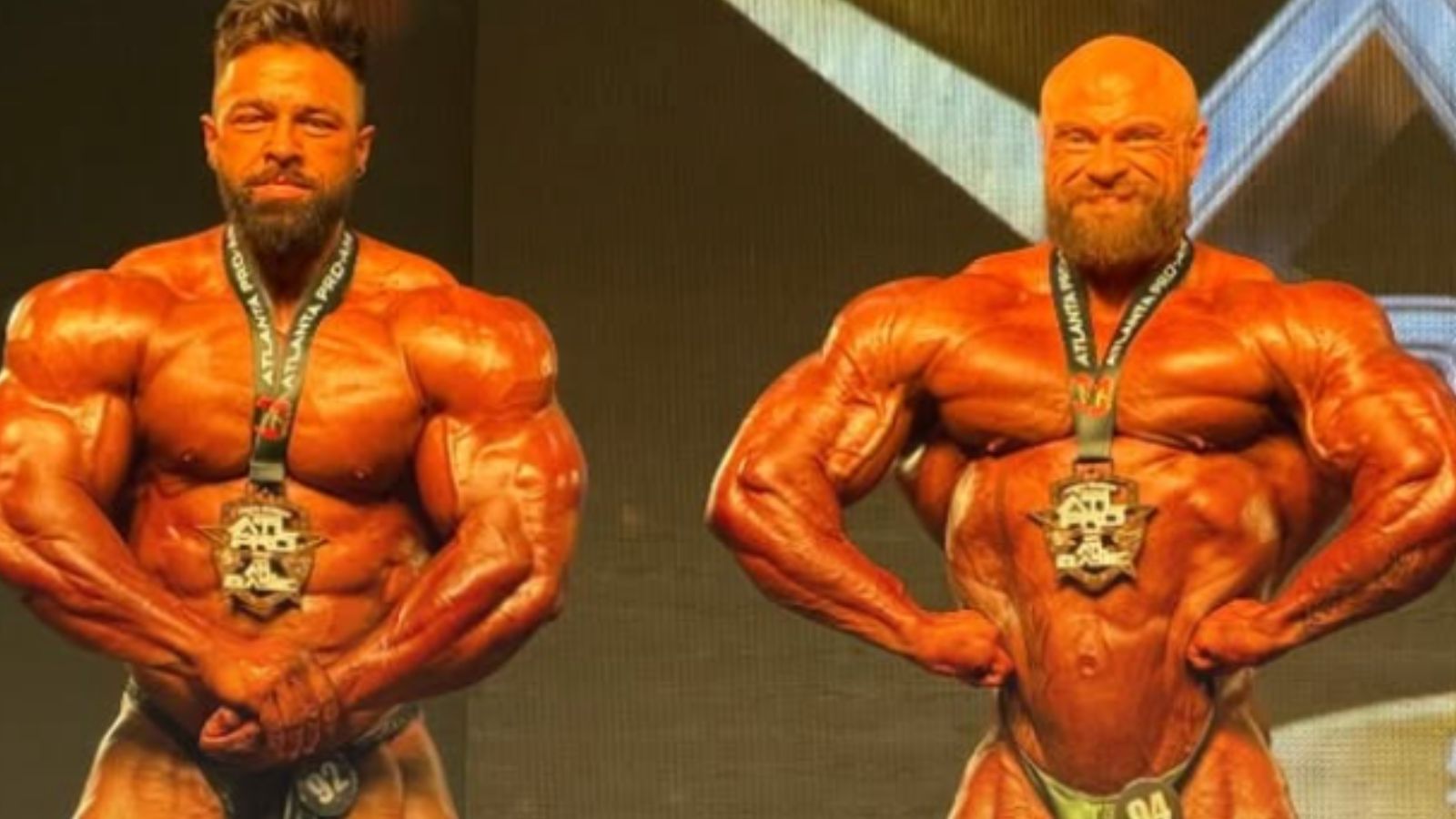 James Hollingshead segura o troféu de ouro na palco iluminado, com barras de ferro ao fundo e luzes de competição