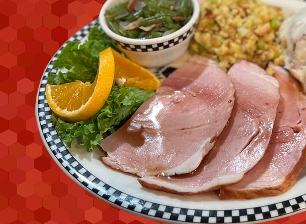 Um prato de frango assado com batata-doce e legumes, servido em um prato de porcelana com uma fatia de pão na lateral