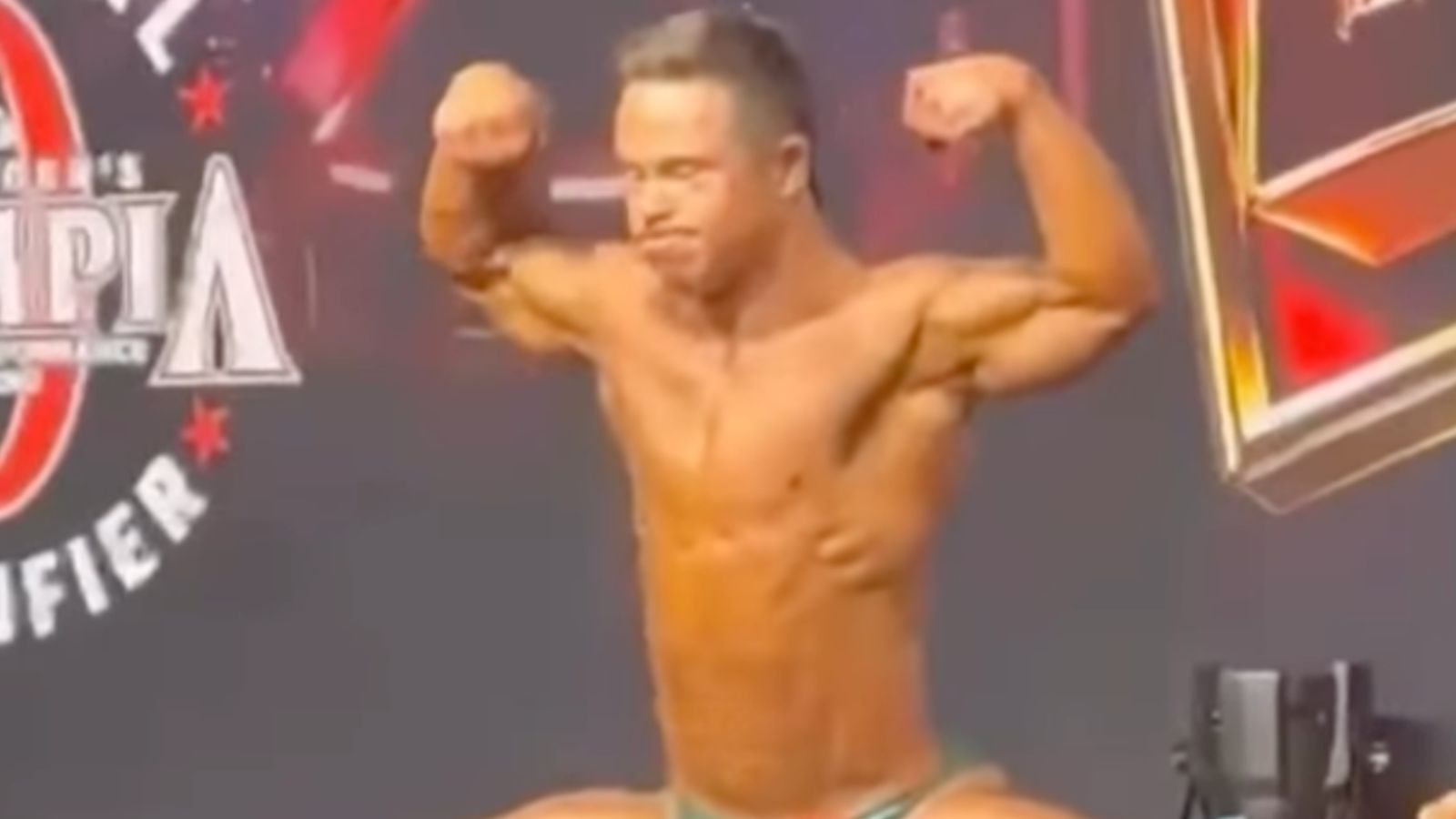 Um homem musculoso em pose, com um prêmio em mãos e um sorriso triunfante, ao fundo uma cidade com edifícios altos