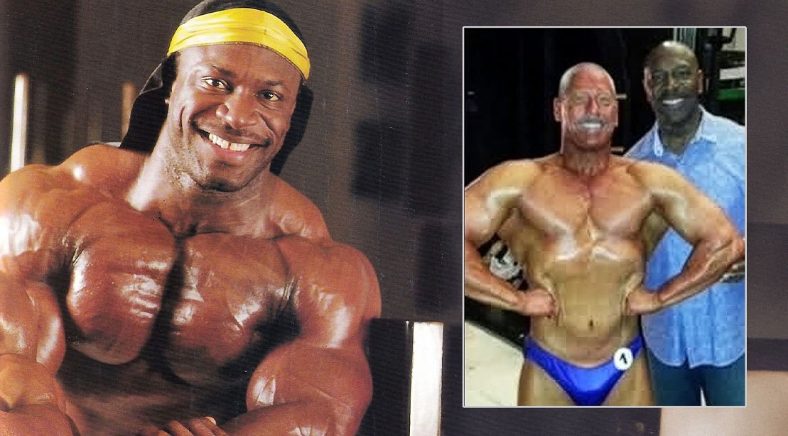 Lee Haney sorrindo ao lado de um médico, segurando um modelo anatômico de rim e um haltere ao fundo