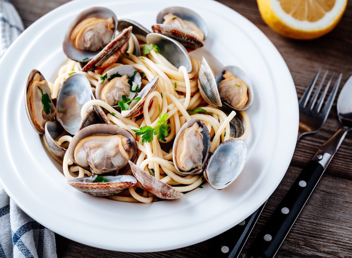 Prato de linguine à vôngole com amêijoas, molho de alho e salsinha, acompanhado de salada verde e copo de água