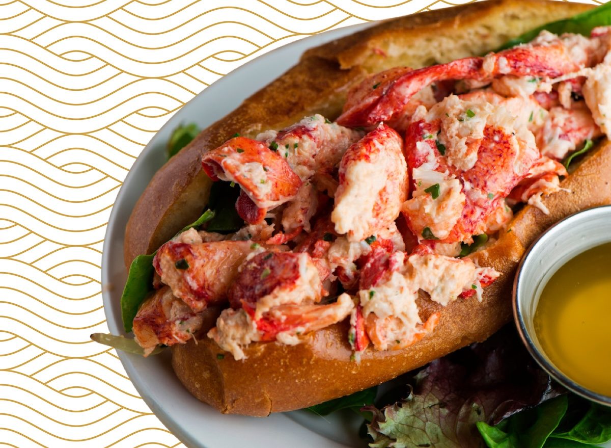 Um prato de lobster grelhado com folhas de alface e um copo de suco de laranja ao lado