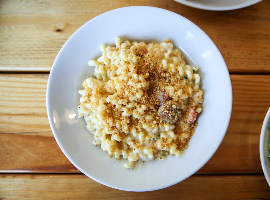 Prato de macarrão com queijo cremoso e dourado, servido em uma mesa rústica com ervas frescas e talheres ao lado