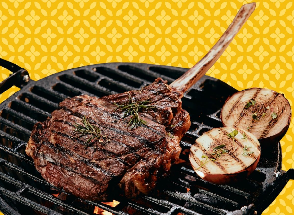 Uma fatia de bife grelhado ao lado de uma tábua com manteiga temperada e ervas frescas