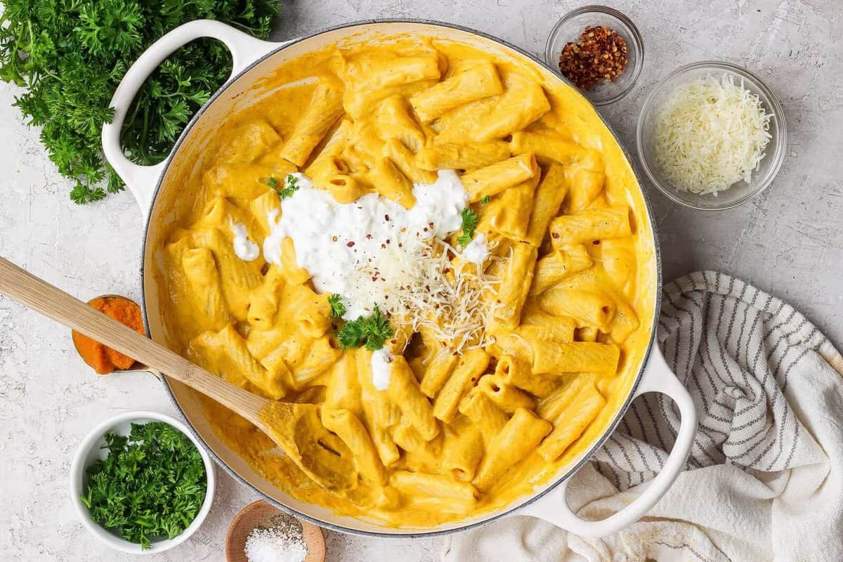 Massa de abóbora dourada ao lado de um pote de cottage cheese, folhas de rúcula e um garfo