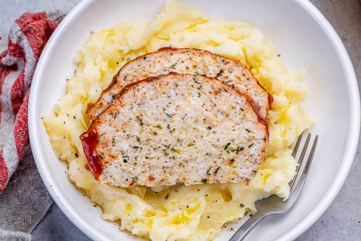 Um prato de meatloaf de frango com parmesão, com fatias bem cortadas e cobertas de queijo derretido