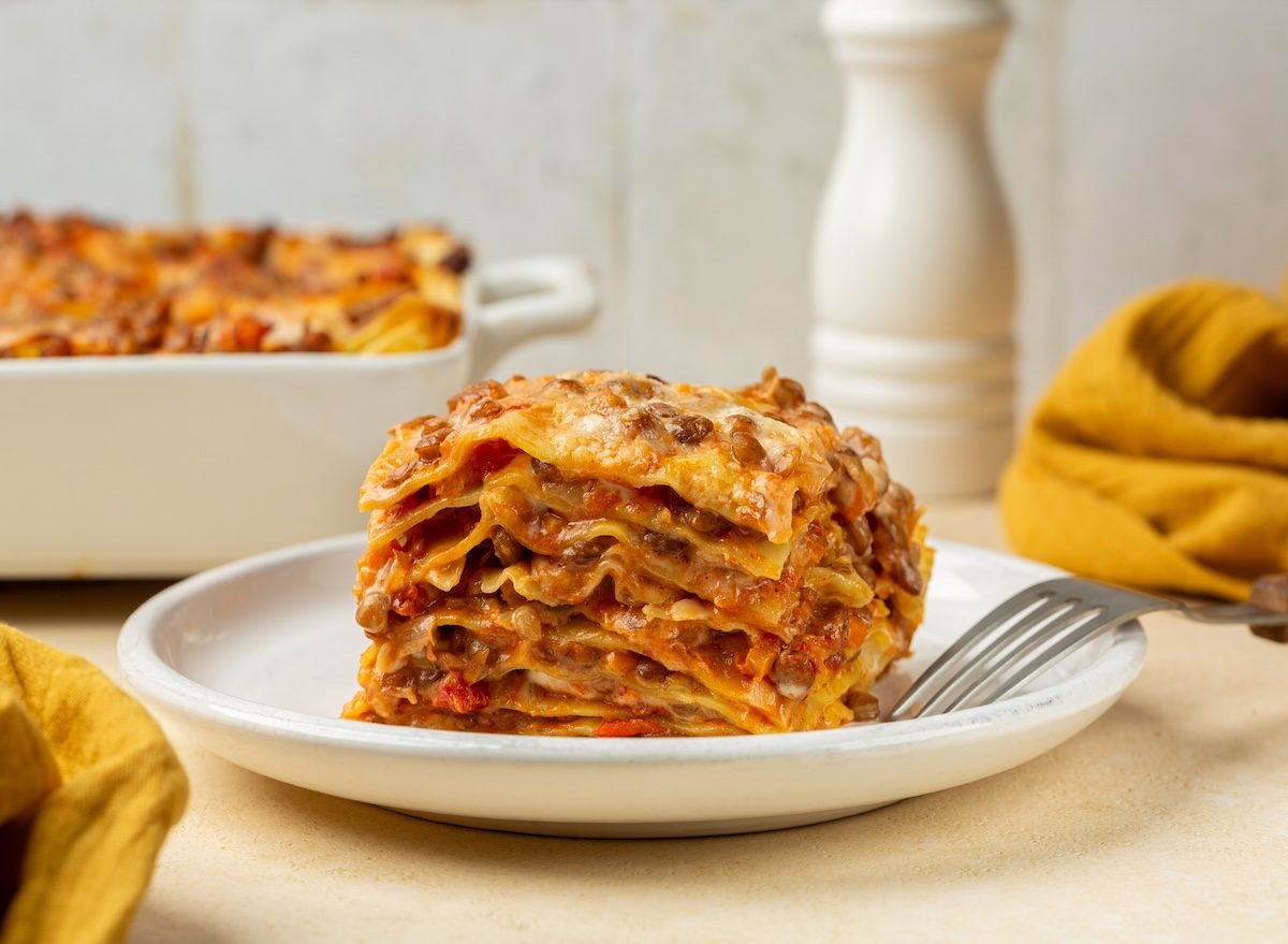 Frasco de molho de tomate industrial ao lado de lasanha pronta, manjericão fresco e uma balança de cozinha