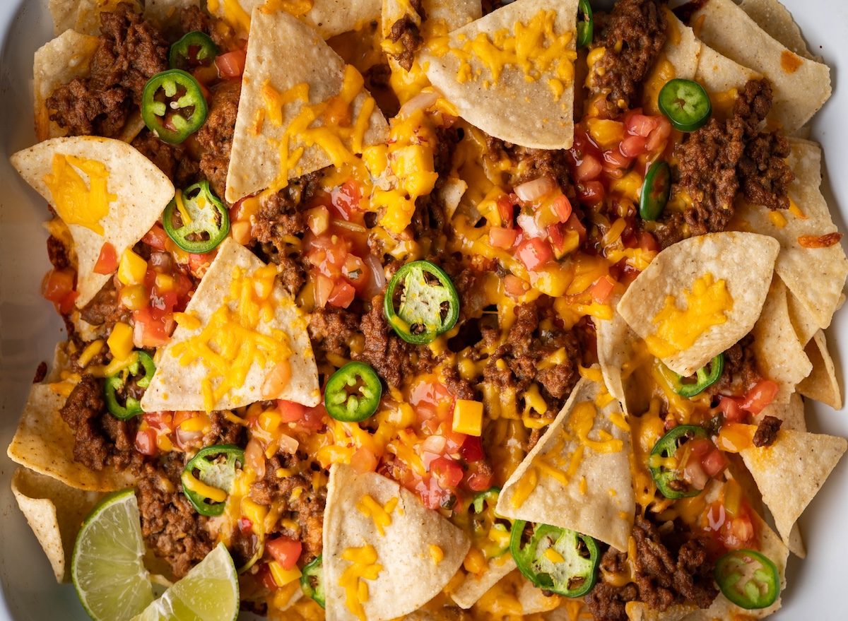 Um prato de nachos crocantes com tortilhas finas, queijos derretidos e vegetais frescos