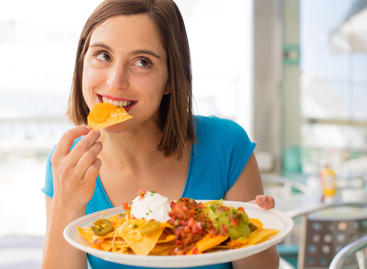 Um prato de nachos crocantes com queijo derretido e legumes frescos, como tomate e cebola