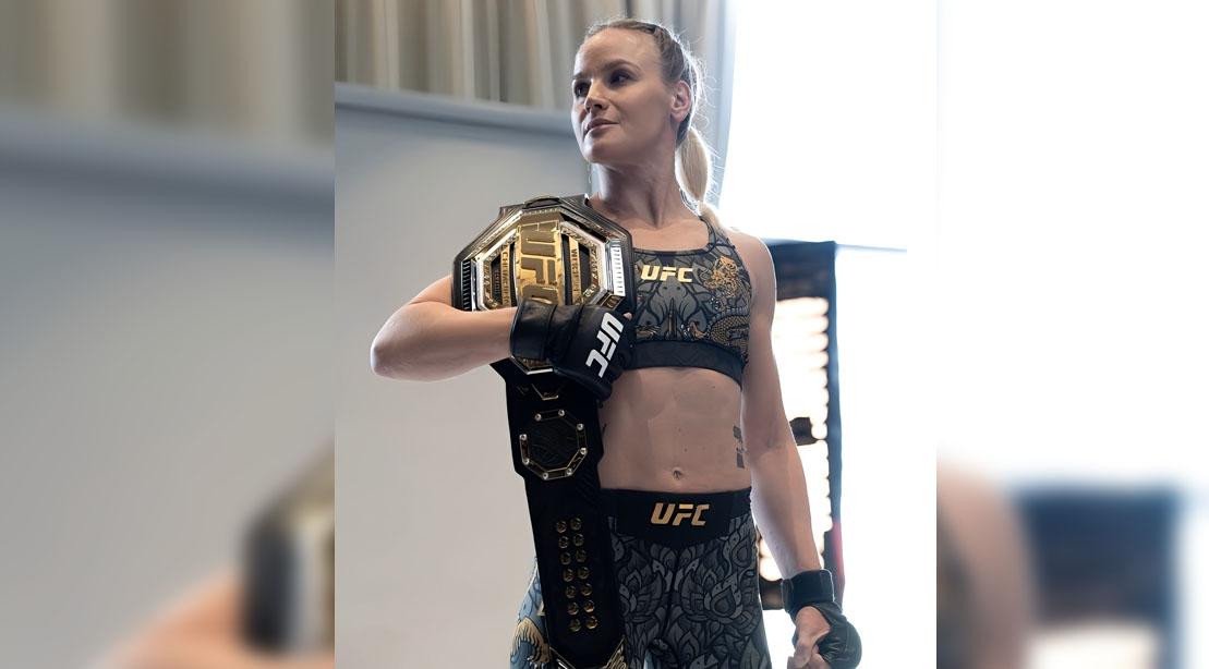 Valentina Shevchenko em pose de luta no octógono, exibindo foco intenso, preparo físico atlético e luvas de MMA