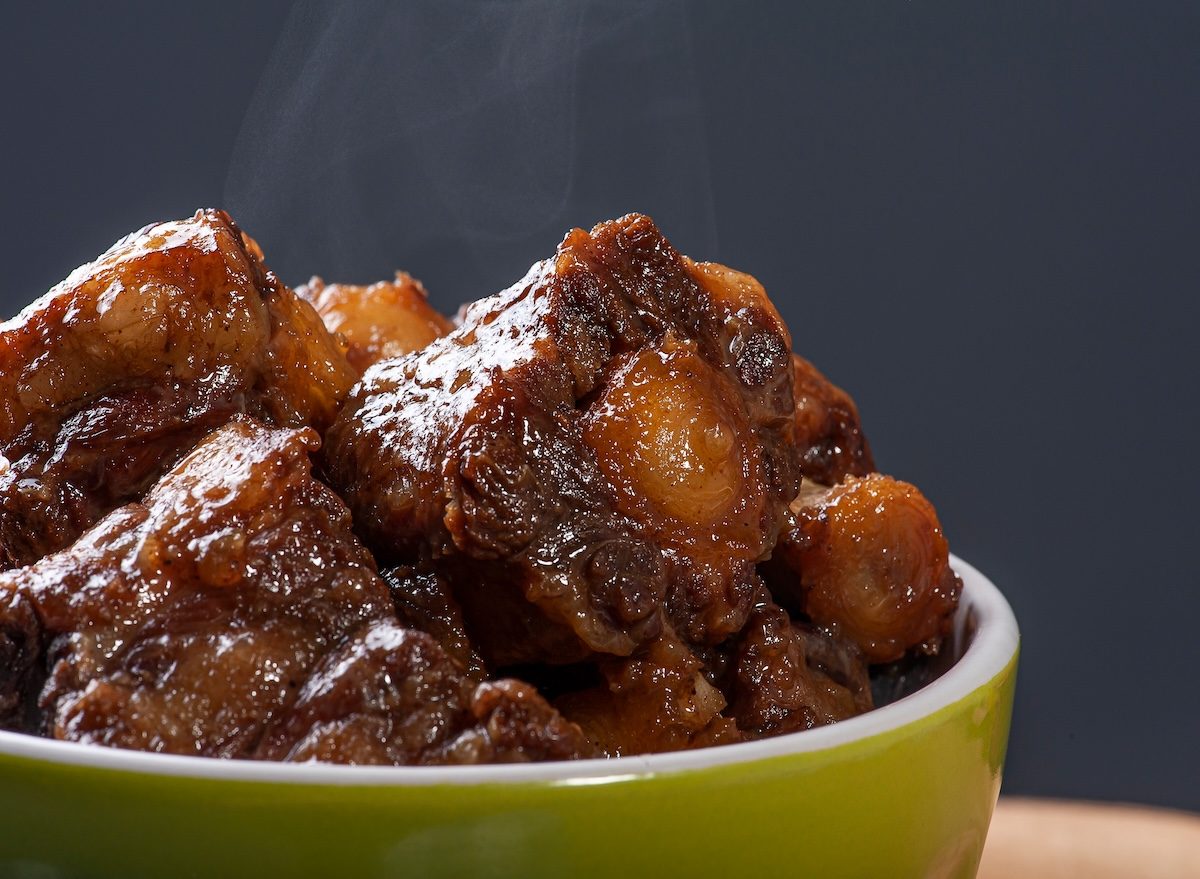 Rabo de boi cozido em panela de ferro, rodeado de cenoura, cebola e alecrim, com caldo espesso e vapor