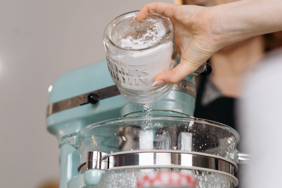 Pote hermético com mix de panqueca ao lado de frutas frescas, iogurte e halteres sobre a bancada da cozinha