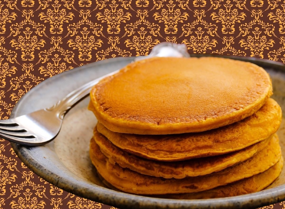 Panquecas douradas de abóbora empilhadas, cobertas com mel, canela em pó e rodelas de nozes ao lado de uma xícara de café