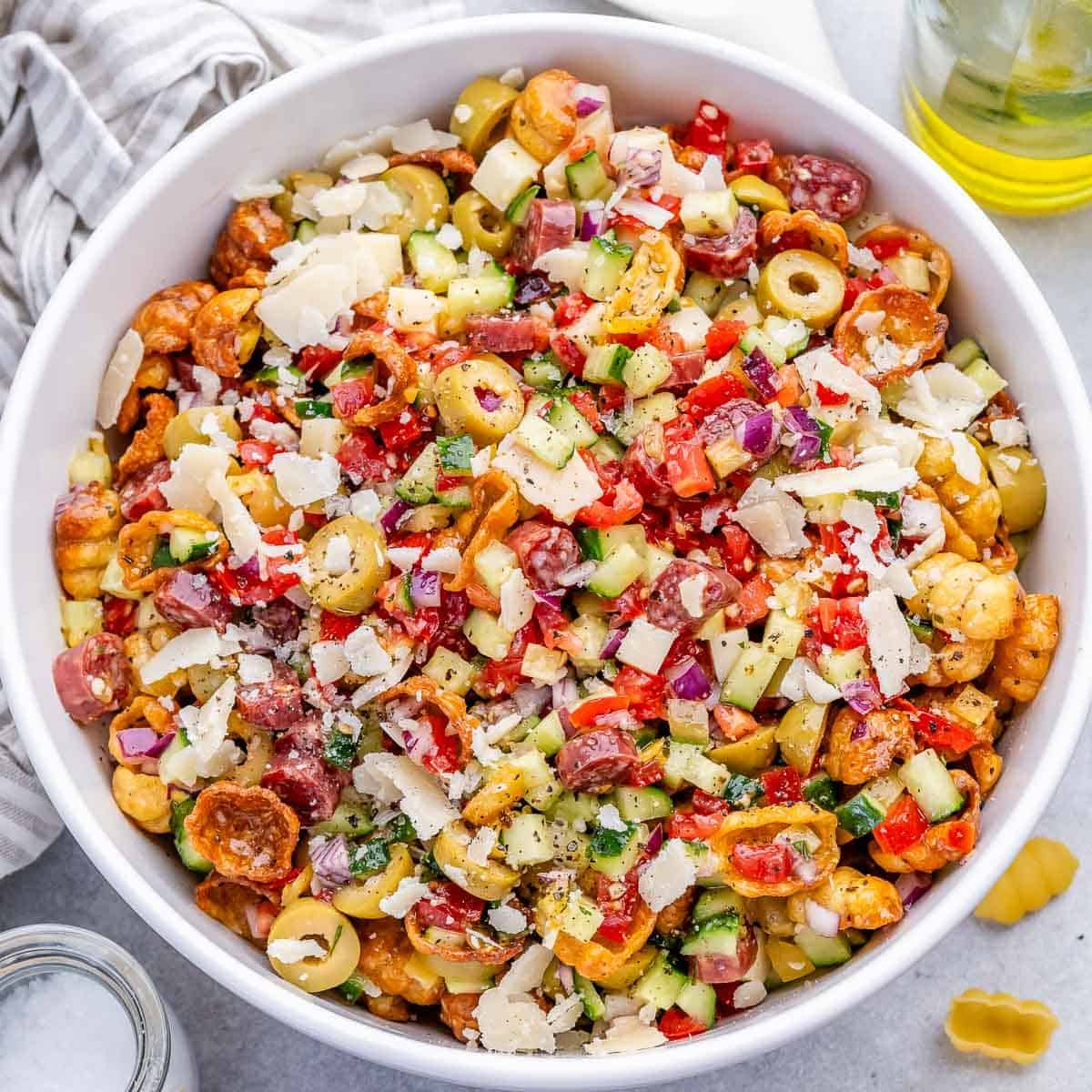 Uma mulher segurando uma colher de sopa de pasta integral, com uma salada fresca ao fundo