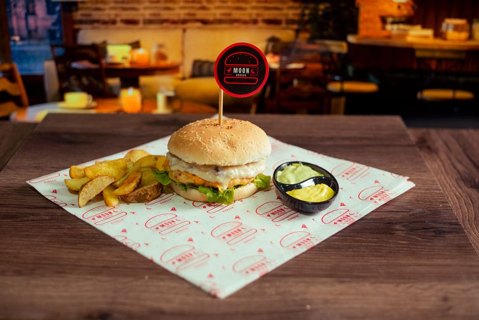 Pessoa em roupa esportiva segurando um patty melt com carne, queijo derretido e pão tostado, ao lado de uma salada verde