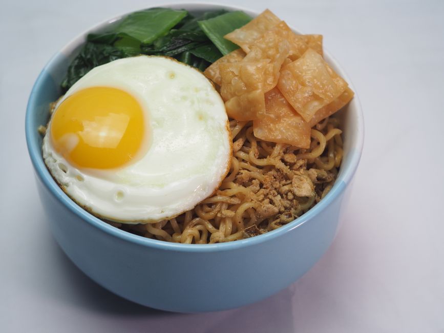 Tigela de noodles veganos com molho de manteiga de amendoim, curry, brócolis e pimentões coloridos, tudo pronto