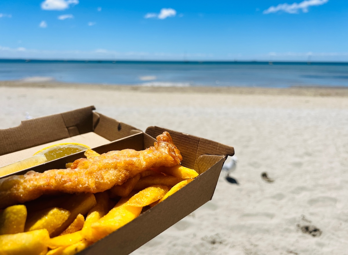Filé de peixe dourado e crocante em um prato, acompanhado de rodelas de limão e ervas frescas sobre uma mesa rústica